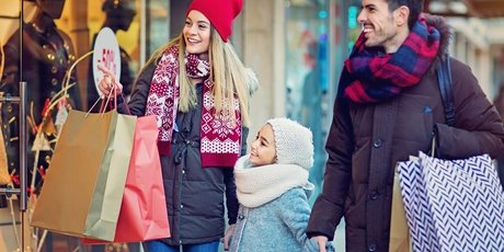 Parents and child strolling happily by the shop window in winter and smiling